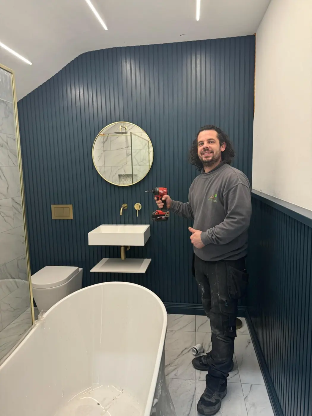 Ash on site in a finished bathroom with navy slatted walls